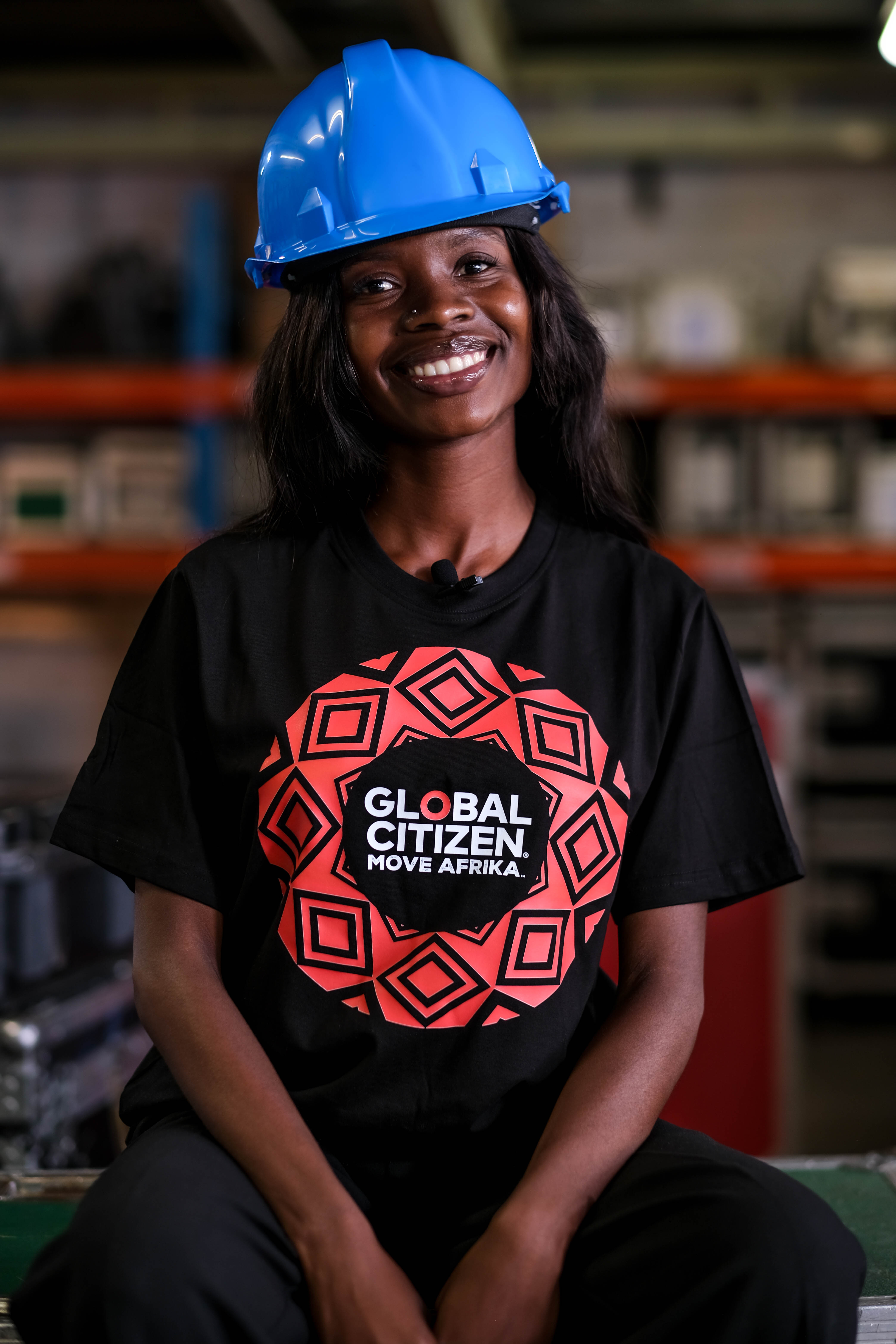 Lutendo Madamela poses at a technical production facility, wearing a hard hat and Global Citizen T-shirt after a day of training.