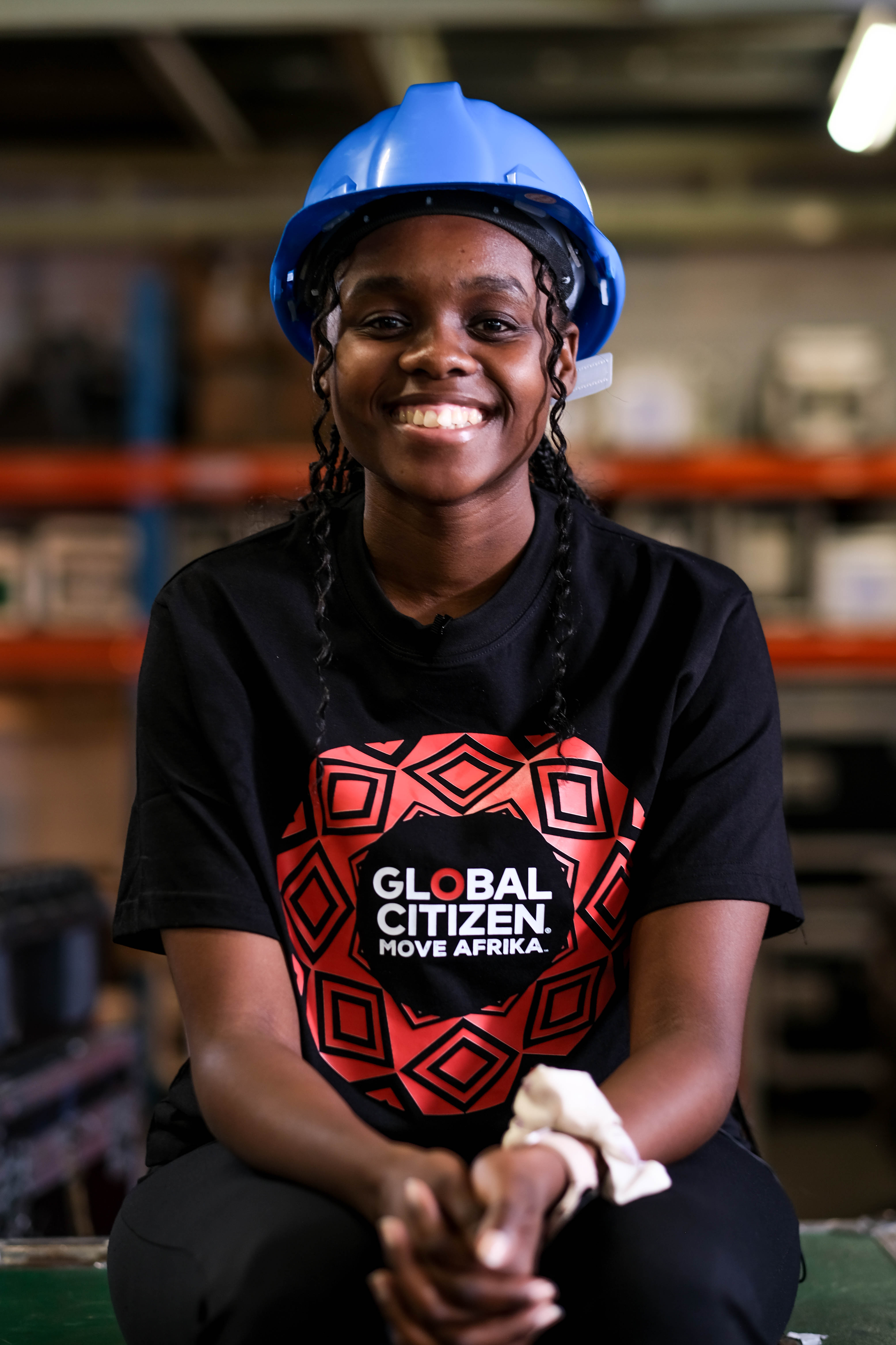 Lulutho Mhlaba wears a hard hat and Global Citizen T-shirt at a technical production facility at Gearhouse.